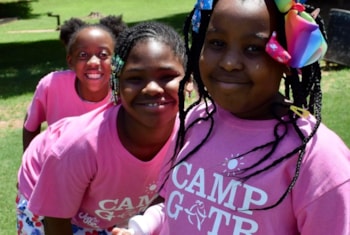 a Camp GOTR participant smiles in a yellow shirt while high-fiving her teammates